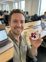 Liam B at his desk holding a PAX Cherry Cola tin